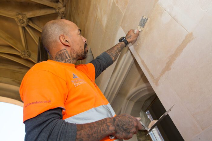 Stonemason restoring stone wall cladding at Kings College at Cambridge University.