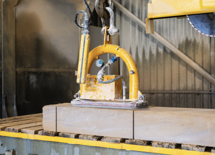 A stone saw cutting a large block of masonry stone for a window dressing.